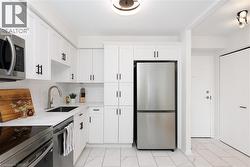 Contemporary kitchen featuring white cabinetry with black hardware, stainless steel appliances, a subway tile backsplash, and a single-basin sink with a gooseneck faucet - 