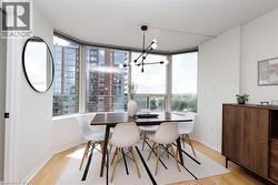 Bay window dining area featuring light wood-finish flooring, a contemporary chandelier, and a wood-finish credenza - 