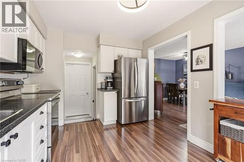 Kitchen featuring wood-finish flooring, white cabinetry, and dark countertops with integrated sink - 2089 Broadleaf Crescent, Burlington, ON 