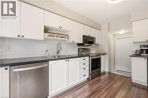 Kitchen featuring white cabinetry with black hardware, dark speckled countertops, and a subway tile backsplash - 2089 Broadleaf Crescent, Burlington, ON 