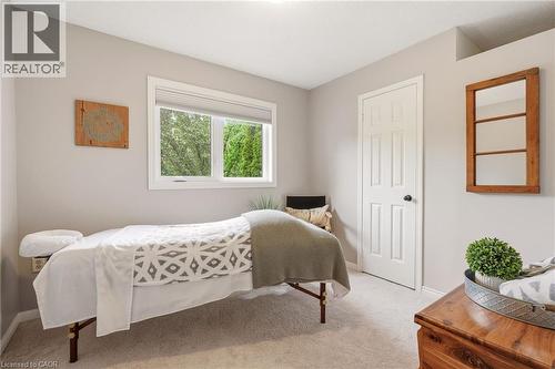 Neutral-toned room featuring a large window, carpet flooring, and a six-panel interior door with a black doorknob - 2089 Broadleaf Crescent, Burlington, ON 