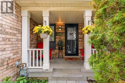 Brick exterior featuring a covered porch with white columns, a dark entry door, and stone steps - 2089 Broadleaf Crescent, Burlington, ON 