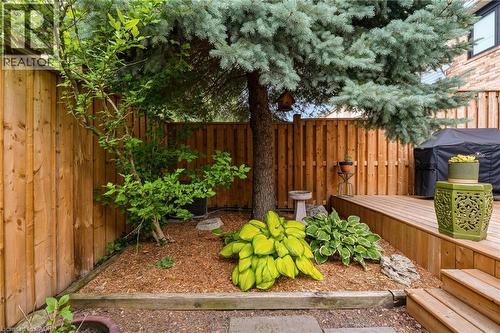 Private backyard space featuring a wood fence, mature trees, and a multi-level wood deck - 2089 Broadleaf Crescent, Burlington, ON 