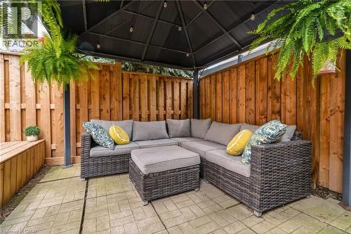 Outdoor patio featuring a dark metal gazebo, wood privacy fencing, and patterned paver flooring - 2089 Broadleaf Crescent, Burlington, ON 