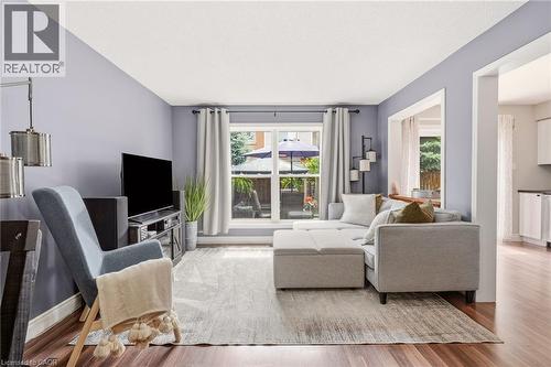 Living area featuring wood-finish flooring, a large window with white trim, and a wide cased opening - 2089 Broadleaf Crescent, Burlington, ON 