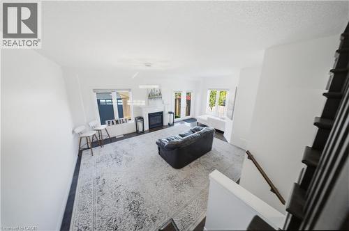 Open-concept living space featuring wood-finish flooring, a white-painted fireplace with a dark insert, and white walls - 104 Sonoma Valley Crescent, Hamilton, ON - Indoor With Fireplace