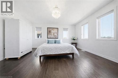Spacious interior with dark wood-finish flooring, multiple windows, and a prominent chandelier - 104 Sonoma Valley Crescent, Hamilton, ON - Indoor Photo Showing Bedroom