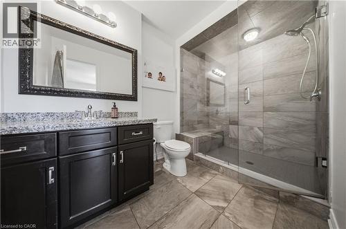Bathroom featuring a glass-enclosed shower with a built-in bench, a rain showerhead, and wall-mounted tile - 104 Sonoma Valley Crescent, Hamilton, ON - Indoor Photo Showing Bathroom
