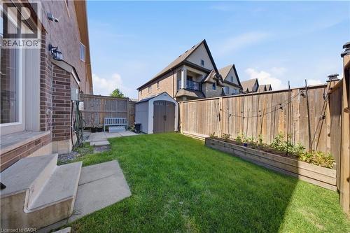 Fenced backyard featuring a manicured lawn, concrete patio steps, and a built-in garden bed - 104 Sonoma Valley Crescent, Hamilton, ON - Outdoor