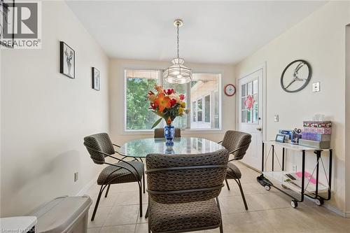 Dining area featuring a glass-top table, suspended lighting fixture, large window, and tile flooring - 176 Sandford Fleming Drive, Waterloo, ON - Indoor Photo Showing Dining Room
