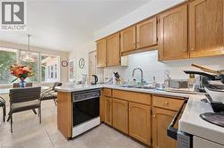 Functional kitchen featuring wood cabinetry, white tile backsplash, a stainless steel sink, and a built-in dishwasher - 