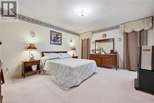 Carpeted room featuring a ceiling-mounted light fixture and textured white walls with a decorative border - 176 Sandford Fleming Drive, Waterloo, ON - Indoor Photo Showing Bedroom