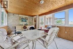 Sunroom featuring a wood-paneled ceiling, exposed brick wall, and multiple windows - 