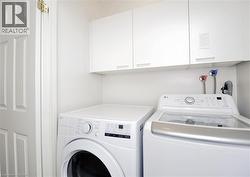 Dedicated laundry area featuring white cabinetry, a white panel door, and prominent washer/dryer connections - 