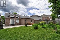 Expansive rear exterior featuring a red brick facade, a large patio area, and a lush green lawn - 