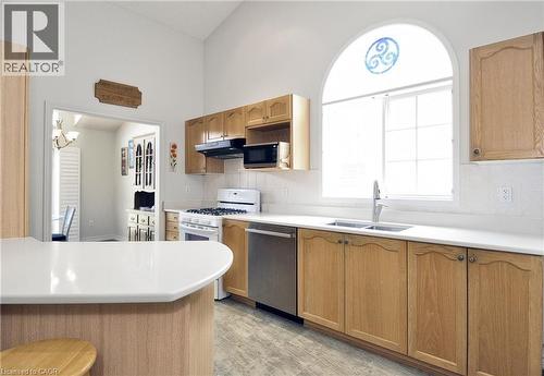Kitchen featuring wood cabinetry, white countertops, stainless steel dishwasher, white gas range, and an arched window with decorative glass - 95 Drinkwater Drive, Cambridge, ON - Indoor Photo Showing Kitchen With Double Sink