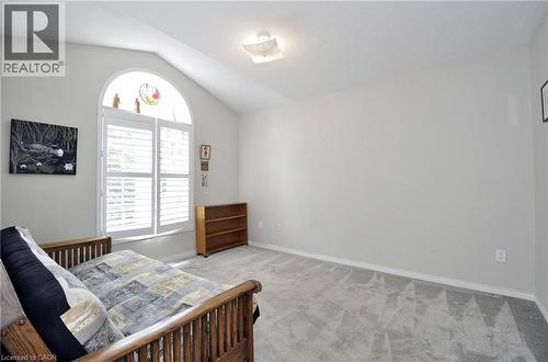 Vaulted ceiling room featuring a large arched window with plantation shutters, light gray wall tones, and gray carpeting - 95 Drinkwater Drive, Cambridge, ON - Indoor Photo Showing Bedroom