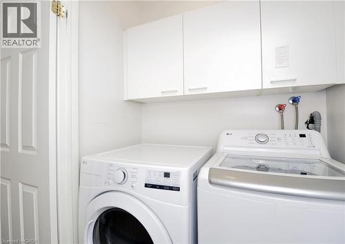 Dedicated laundry area featuring white cabinetry, a white panel door, and prominent washer/dryer connections - 95 Drinkwater Drive, Cambridge, ON - Indoor Photo Showing Laundry Room