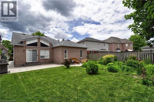 Expansive rear exterior featuring a red brick facade, a large patio area, and a lush green lawn - 95 Drinkwater Drive, Cambridge, ON - Outdoor