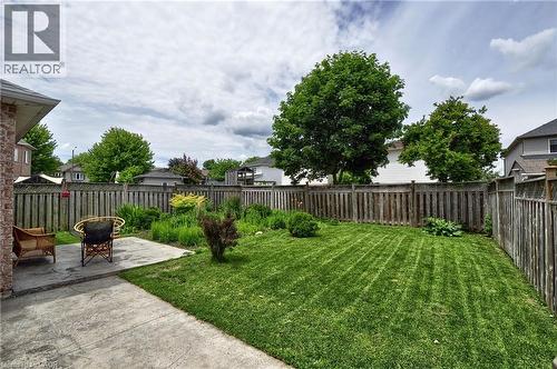 Expansive backyard featuring a concrete patio, lush green lawn, mature trees, and a full perimeter wood fence - 95 Drinkwater Drive, Cambridge, ON - Outdoor With Backyard