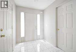 Entryway featuring white tile flooring and a solid white door with sidelight windows - 
