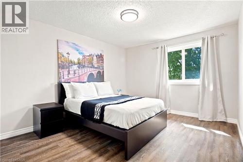 Bedroom featuring wood-finish flooring, a double-paned window, and a flush-mount ceiling light - 175 Siebert Avenue Unit# 9, Kitchener, ON 