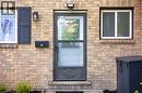 Front entryway featuring a brick facade, transom window, storm door, wall-mounted light fixture, and black shutters - 175 Siebert Avenue Unit# 9, Kitchener, ON 