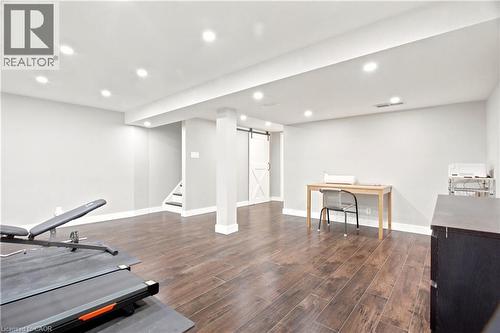 Spacious room featuring wood-finish flooring, recessed lighting, and a white barn door - 175 Siebert Avenue Unit# 9, Kitchener, ON 