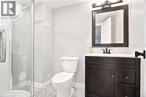 Bathroom featuring a glass-enclosed shower, dark wood-finish vanity with a white countertop, matte black faucet, and a framed mirror with overhead lighting - 175 Siebert Avenue Unit# 9, Kitchener, ON 