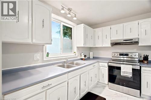 Modern kitchen featuring white cabinetry, a double basin stainless steel sink, sleek stainless steel appliances, track lighting, and a window with natural light - 175 Siebert Avenue Unit# 9, Kitchener, ON 