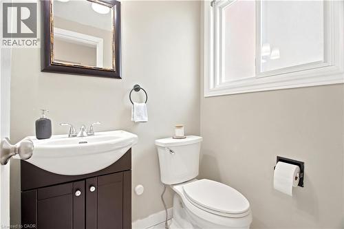 Powder room featuring a dark wood-finish vanity with a white ceramic sink, chrome faucet, and a framed mirror - 175 Siebert Avenue Unit# 9, Kitchener, ON 