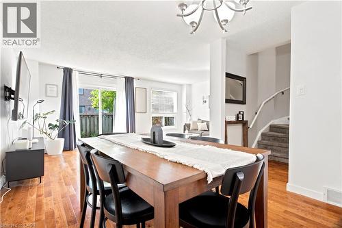 Open-concept dining area featuring wood-finish flooring, a contemporary chandelier, and direct patio access through sliding glass doors - 175 Siebert Avenue Unit# 9, Kitchener, ON 