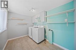 Dedicated laundry space featuring neutral tile flooring, a window with horizontal blinds, and overhead track lighting - 