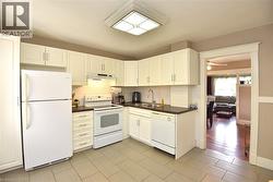 Kitchen featuring white cabinetry, dark countertops, a tile backsplash, and light tile flooring - 