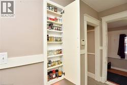 Tall built-in pantry cabinet with multiple shelves, featuring a white door and trim - 