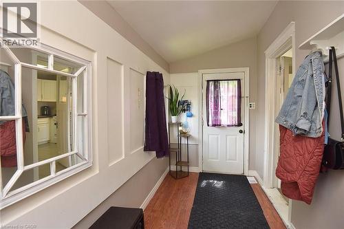 Entryway featuring wood-finish flooring, a white paneled accent wall, and a white framed mirror - 56 Barons Avenue N, Hamilton, ON 