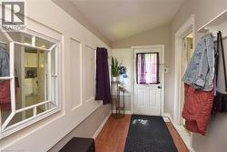Entryway featuring wood-finish flooring, a white paneled accent wall, and a white framed mirror - 