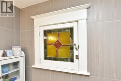 Built-in cabinet with stained glass door and decorative white trim - 