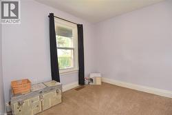 Carpeted room featuring a single window with dark drapery, light-colored walls, and white baseboards - 