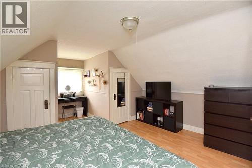 Attic space featuring wood-finish flooring, an angled ceiling, white trim, and a window - 56 Barons Avenue N, Hamilton, ON 