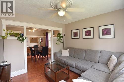 Living area featuring wood-finish flooring, a ceiling fan with decorative medallion, and a wide cased opening to an adjacent room - 56 Barons Avenue N, Hamilton, ON 