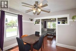 Dining area with wood-finish flooring, a ceiling fan with light fixture, and a window featuring white trim - 
