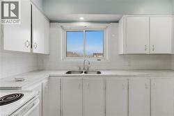 Kitchen featuring white cabinetry, white subway tile backsplash, a double basin stainless steel sink, and a white electric range - 