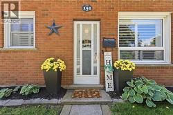 Brick exterior facade featuring a white entry door with glass paneling, two white-framed windows, and a concrete walkway - 