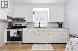 Kitchen featuring white cabinetry, light-toned countertops, tile flooring, a stainless steel range, and a window with blinds - 