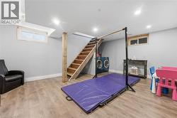 Finished lower level featuring recessed lighting, wood-finish flooring, light grey wall paint, and exposed wood structural support - 