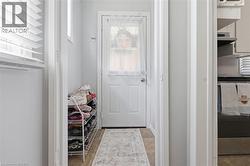 Entryway with a white paneled door featuring a privacy window and light-toned flooring - 