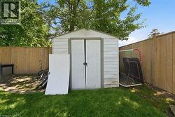 Dedicated storage shed featuring a dual-door entry, a level concrete foundation, and a surrounding privacy fence - 