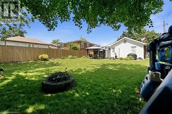 Expansive green lawn featuring a built-in fire pit, privacy fencing, and a permanent gazebo structure - 