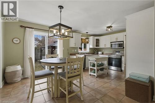 Kitchen and dining area featuring white cabinetry, stainless steel appliances, a center island on casters, and tiled flooring - 84 Duncairn Crescent, Hamilton, ON 